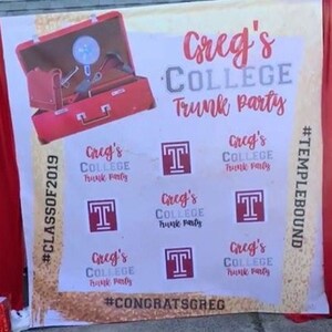 May include: A white banner with red trim and a red suitcase with a fan inside. The banner has the text "Creg's College Trunk Party" and "#CLASSOF2019" on the left side. The banner also has the text "#TEMPLEBOUND" on the right side. The banner has several red "T" logos and the text "Creg's College Trunk Party" repeated several times. The banner also has the text "#CONGRATSGREG" at the bottom.