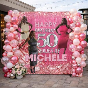 May include: A pink backdrop with the text "HAPPY BIRTHDAY 50 SHADES OF MICHELE" is surrounded by pink and white balloons. Three women are posing in front of the backdrop. A floral arrangement and silver spheres are in the foreground.