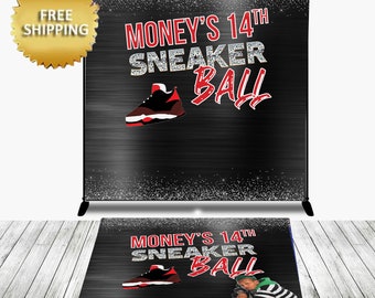 May include: Black and silver backdrop with the text "Money's 14th Sneaker Ball" in red and white. A red and black sneaker is pictured above the text. The backdrop is designed for a party or event.