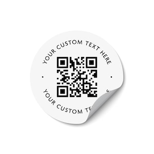 Może przedstawiać: Okrągła biała naklejka z czarnym kodem QR pośrodku. Tekst "YOUR CUSTOM TEXT HERE" jest wydrukowany czcionką bezszeryfową w kolorze czarnym, wygiętą wzdłuż g&oacute;rnej i dolnej krawędzi. Prawy dolny r&oacute;g naklejki jest lekko odklejony od podłoża.
