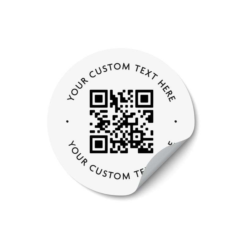 Może przedstawiać: Okrągła biała naklejka z czarnym kodem QR pośrodku. Tekst "YOUR CUSTOM TEXT HERE" jest wydrukowany czcionką bezszeryfową w kolorze czarnym, wygiętą wzdłuż g&oacute;rnej i dolnej krawędzi. Prawy dolny r&oacute;g naklejki jest lekko odklejony od podłoża.