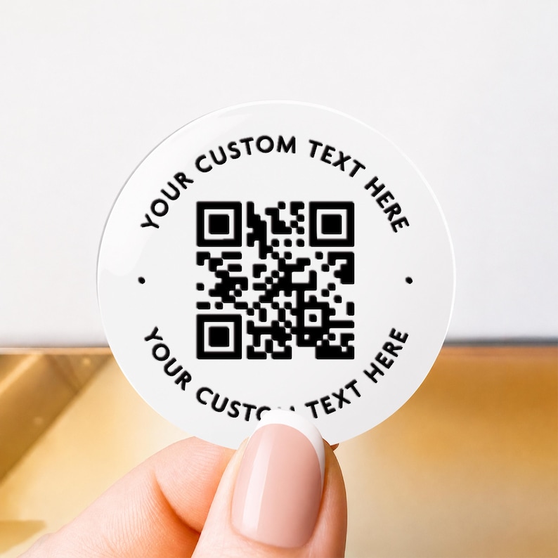 Może przedstawiać: Okrągła biała naklejka z czarnym kodem QR pośrodku. Tekst "YOUR CUSTOM TEXT HERE" jest wydrukowany czarnymi wielkimi literami wzdłuż g&oacute;rnej i dolnej krawędzi naklejki, z małymi czarnymi kropkami po lewej i prawej stronie.