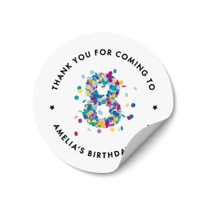 May include: A white, circular sticker with a curled edge. The sticker displays the text "THANK YOU FOR COMING TO AMELIA'S BIRTHDAY" in black, encircling a colourful confetti-filled number 8. Two small black stars are also present.