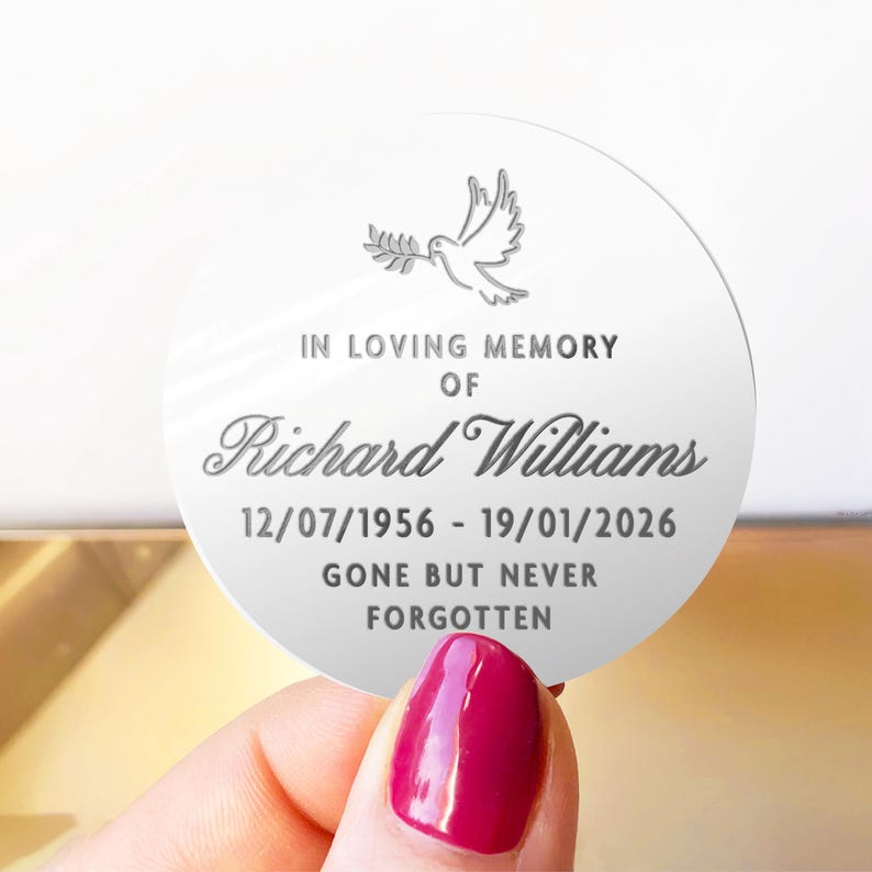 May include: A round, white memorial keepsake with the text "IN LOVING MEMORY OF Richard Williams 12/07/1956 - 19/01/2026 GONE BUT NEVER FORGOTTEN." A dove with an olive branch is at the top.