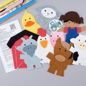 May include: A felt farm play set with a red barn, a white cow, a brown horse, a pink pig, a gray goat, a white sheep, a yellow duck, a white chicken, a brown haired girl wearing overalls, and a green tractor.