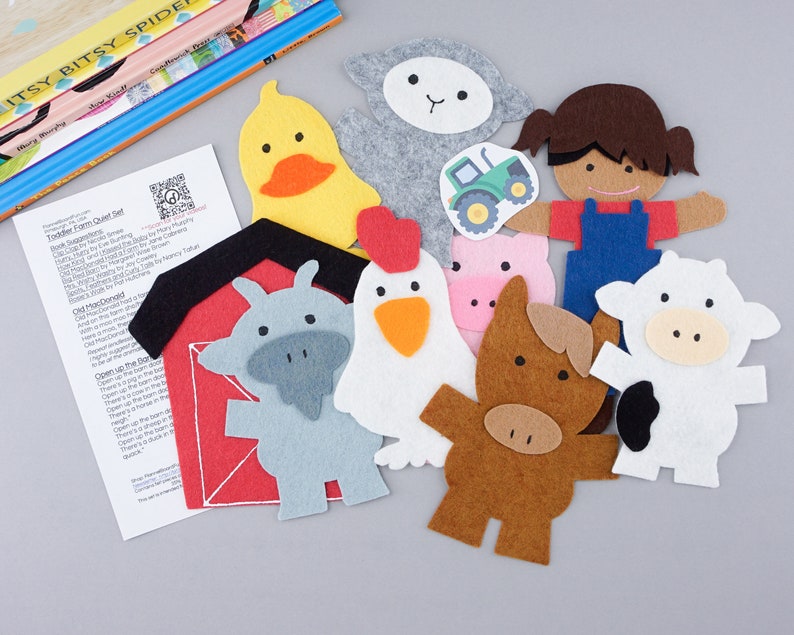 May include: A felt farm play set with a red barn, a white cow, a brown horse, a pink pig, a gray goat, a white sheep, a yellow duck, a white chicken, a brown haired girl wearing overalls, and a green tractor.