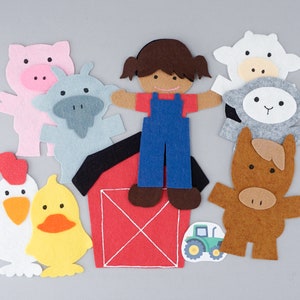 May include: Felt farm animal figures, including a pig, cow, sheep, horse, and a girl wearing overalls. The figures are standing in front of a red barn with a white X on the front. There is also a yellow chick and a tractor.