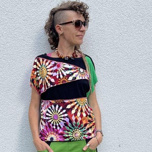 Peut inclure: Un haut à manches courtes avec une base noire et des motifs floraux multicolores vifs sur la poitrine et l'épaule, associé à un pantalon vert vif ample doté de bandes latérales noires et de bords élastiqués au niveau des chevilles.
