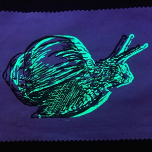 UV-active upcycling patch, black-neon green snail, hand-printed patch, two-tone stamp print, fluorescent, animal motif, rave