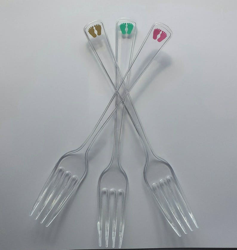 Peut inclure: Trois fourchettes en plastique transparent avec des empreintes de pieds dor&eacute;es, vertes et roses imprim&eacute;es sur les manches.