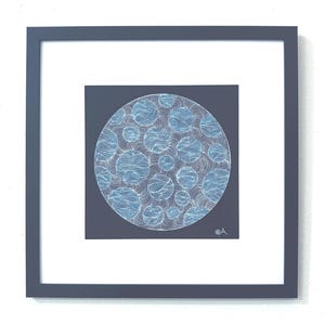 May include: A square framed artwork featuring a circular design on a dark gray background. The circle contains multiple smaller light blue spheres filled with intricate white line patterns, surrounded by flowing white lines throughout the space.