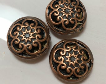 May include: Three copper-colored buttons with a decorative, intricate, black filigree design.