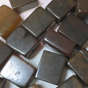 May include: A collection of brown and black square-shaped beads. The beads are made of a smooth, polished material.