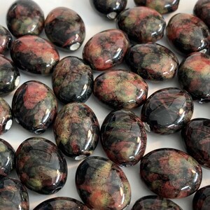 May include: A collection of oval-shaped, polished stones with a black, green, and red marbled pattern.