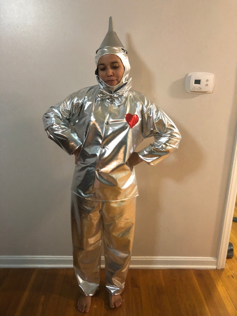 K&ouml;nnte beinhalten: Eine Person tr&auml;gt ein silberfarbenes Metallic-Kost&uuml;m mit einem roten Herzen auf der Brust. Das Kost&uuml;m ist eine Nachbildung des Blechmanns aus dem Zauberer von Oz.