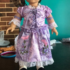 May include: A purple satin dress with a lace overlay and embroidered butterflies. The dress has a fitted bodice with a lace-up front and a full skirt.