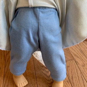 Puede incluir: Un pantal&oacute;n azul claro con una parte superior blanca y plateada brillante. El pantal&oacute;n est&aacute; hecho de una tela suave y c&oacute;moda y tiene un ajuste holgado.