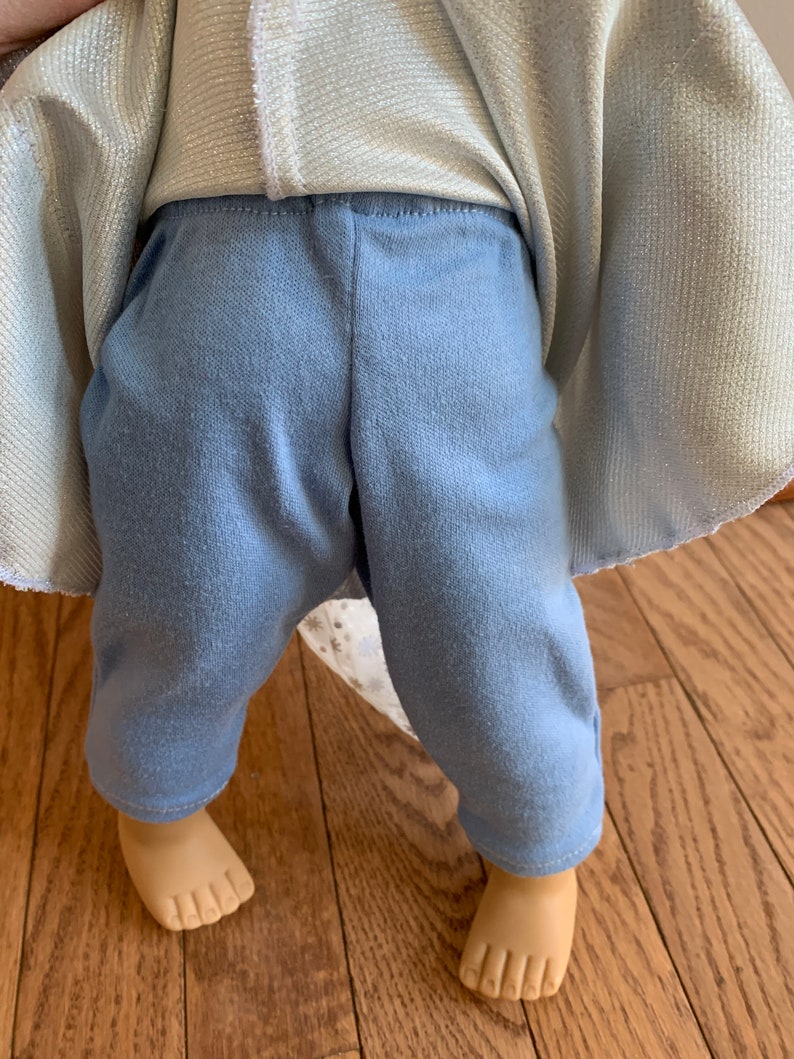 Puede incluir: Un pantal&oacute;n azul claro con una parte superior blanca y plateada brillante. El pantal&oacute;n est&aacute; hecho de una tela suave y c&oacute;moda y tiene un ajuste holgado.