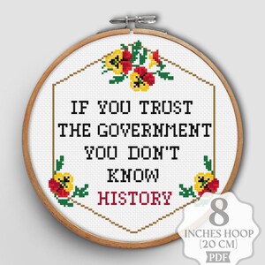 以下が含まれることがあります： 木製のフレームに入ったクロスステッチ刺繍。テキストは黒い文字で「IF YOU TRUST THE GOVERNMENT YOU DON'T KNOW HISTORY」と書かれています。赤、黄、緑の花柄のアクセント。フレームの直径は20cmです。