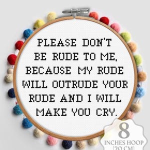 Op de afbeelding: Kruissteekring met de tekst "PLEASE DON'T BE RUDE TO ME, BECAUSE MY RUDE WILL OUTRUDE YOUR RUDE AND I WILL MAKE YOU CRY." De ring heeft een diameter van 20 cm en is versierd met kleurrijke pompons.