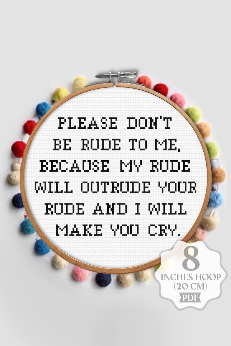 Op de afbeelding: Kruissteekring met de tekst "PLEASE DON'T BE RUDE TO ME, BECAUSE MY RUDE WILL OUTRUDE YOUR RUDE AND I WILL MAKE YOU CRY." De ring heeft een diameter van 20 cm en is versierd met kleurrijke pompons.