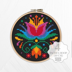 May include: A colorful cross-stitch pattern of a stylized flower in a 4 inch embroidery hoop. The pattern is worked in shades of red, orange, yellow, green, blue, and purple on a black background. The text "4 INCHES HOOP (10 CM) PDF" is printed on a white circle.