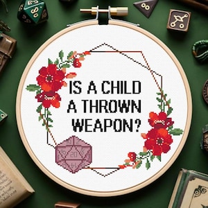 Puede incluir: Bordado de punto de cruz con el texto "IS A CHILD A THROWN WEAPON?" rodeado de flores rojas y hojas verdes. Un dado morado de 20 caras en la parte inferior. Fondo verde con dados y libros.