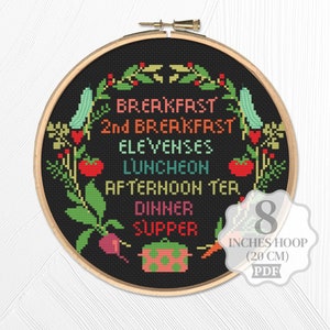 Könnte beinhalten: Ein schwarzer Stickrahmen mit einem bunten Kreuzstich-Design mit den Worten "Frühstück, 2. Frühstück, Elfensnack, Mittagessen, Nachmittagstee, Abendessen, Abendbrot" umgeben von verschiedenen Gemüsesorten und einem Topf. Der Rahmen hat einen Durchmesser von 20 cm.