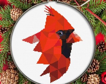 May include: A geometric cross-stitch pattern of a cardinal bird with a red and black color scheme. The design is on a white background and is framed in a wooden hoop.