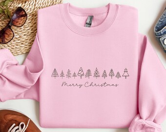 May include: A light pink sweatshirt with a crew neck. The front features a line of minimalist black Christmas tree designs above the words "Merry Christmas" in a cursive font. The sweatshirt is made of a soft material.