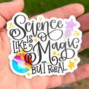 May include: A white sticker with black text that reads "Science is like magic but real." The sticker features a rainbow planet, stars, and a purple wand with a star on top.