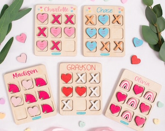 May include: Five wooden game boards with different themes. Each board has a different name at the top, including Charlotte, Chase, Grayson, Madison, and Olivia. The boards are made of light wood and have a grid pattern. The game pieces are made of wood and have different shapes and colours. The game pieces are arranged in a grid pattern on the boards. The boards are on a white surface.