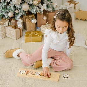 a little girl sitting on the floor next to a christmas tree