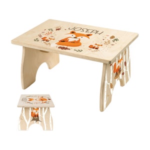 May include: A personalized wooden step stool with a fox family design. The stool is painted with a light wood finish and features a white birch tree pattern. The top of the stool is personalized with the name "Joseph".