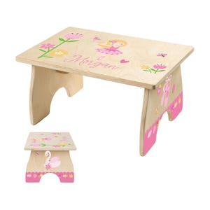 May include: A light-colored wooden children's table with a pink and floral design. The table features a ballerina, flowers, and the name "Morgan" in pink script. The legs are decorated with ballet shoes and a crown.