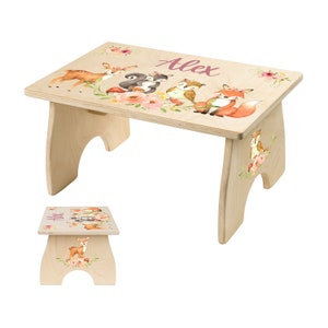 May include: A wooden step stool with a personalized name "Alex" and a woodland animal design. The design features a deer, squirrel, owl, and fox with floral accents.