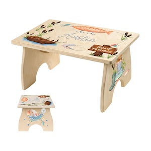 May include: A wooden step stool with a fishing theme. The top features a painted illustration of a fishing lure, a boat, and the name "Austin". The side of the stool has a painted image of a fisherman. The words "Gone Fishing" are on a wooden sign.