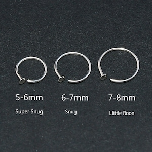 May include: Three silver nose rings of varying sizes, each with a small flat end. The sizes are labeled as 5-6mm, 6-7mm, and 7-8mm, with the text "Super Snug", "Snug", and "Llittle Roon" below each ring.