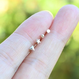 May include: Three silver stud earrings with different shapes: a star, a circle, and a triangle.