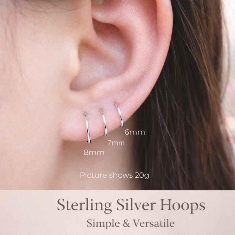 May include: Close-up of an ear with three small, silver hoop earrings of varying sizes: 6mm, 7mm, and 8mm. The text on the image reads "Sterling Silver Hoops" and "Simple & Versatile". The picture shows 20g.