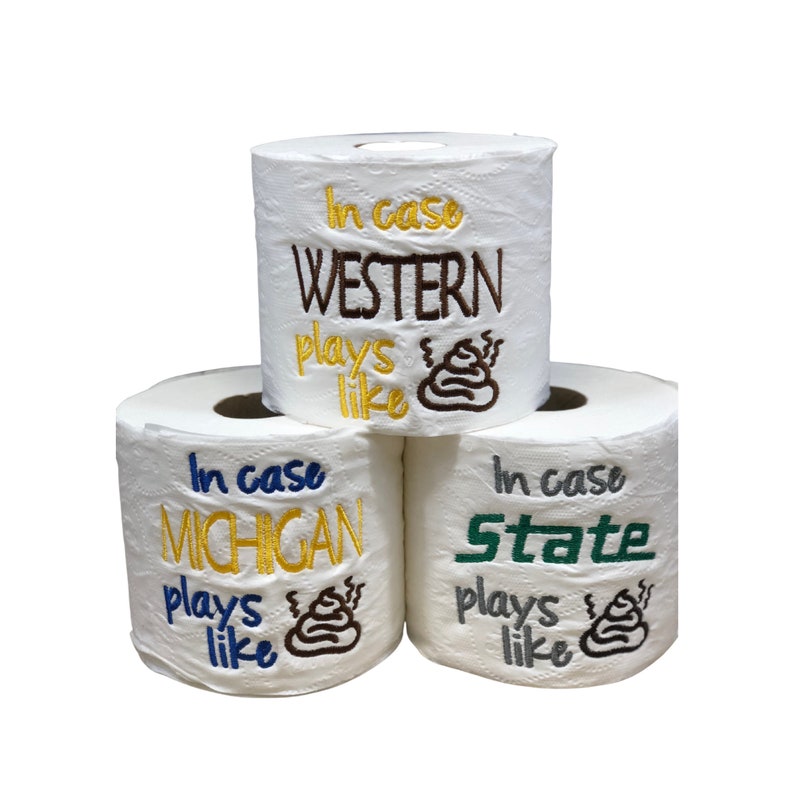 May include: Three rolls of toilet paper with embroidered text. The top roll says "In case WESTERN plays like" with a brown poop emoji. The middle roll says "In case MICHIGAN plays like" with a brown poop emoji. The bottom roll says "In case State plays like" with a brown poop emoji.