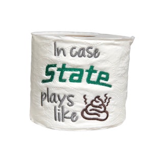 May include: A white toilet paper roll with the text "In case State plays like" and a brown poop emoji embroidered on it.