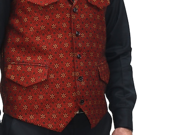 May include: A red vest featuring a repeating dark geometric pattern with small yellow star-like accents. The vest has a notched lapel, five black buttons down the front, two chest pockets with flaps, and two lower pockets with flaps, worn over a black shirt.