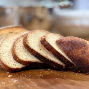 Puede incluir: Rebanadas de pan con corteza dorada y un interior claro, sobre una tabla de cortar de madera. Las rebanadas de pan est&aacute;n dispuestas para mostrar la textura y el color de los productos horneados.