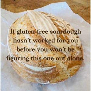 Puede incluir: Una hogaza redonda de pan de masa madre sin gluten con una corteza dorada y una parte superior de color claro, sobre papel de pergamino blanco. El texto en el pan dice: "Si la masa madre sin gluten no te ha funcionado antes, no lo descubrir&aacute;s solo."