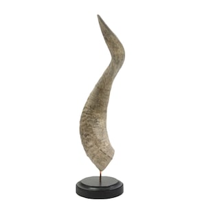May include: A large, curved, grey animal horn mounted on a black wooden base. The horn is smooth and has a natural, weathered look.