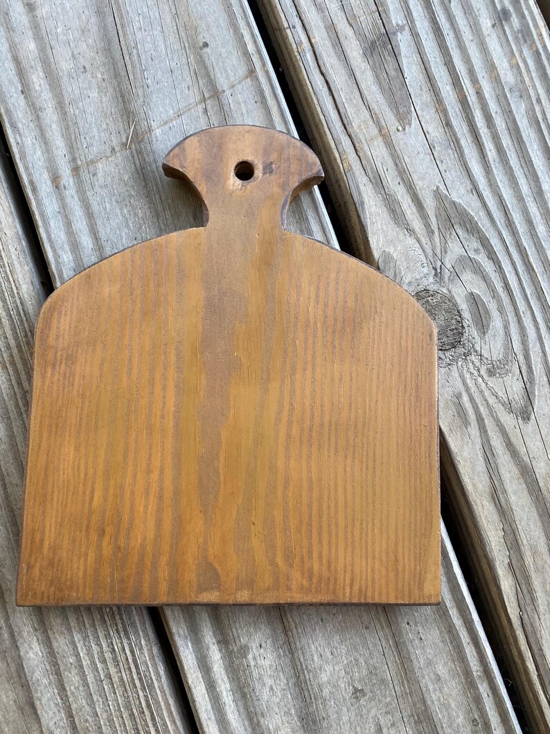 May include: A wooden kitchen utensil with a handle and a flat surface. The utensil is brown and has a natural wood finish.