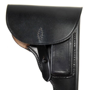 May include: A black leather holster for a handgun. The holster has a flap that covers the top of the gun and a belt loop on the back.