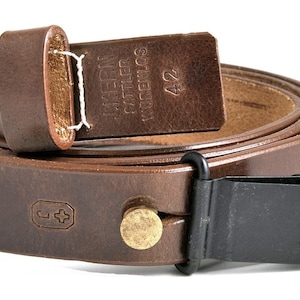 May include: A brown leather rifle sling with a black metal buckle and a brass button. The sling has the text "WAFFEN  SOMMER  24" on the leather strap.