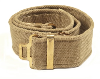 May include: A tan canvas belt with a brass buckle. The belt is rolled up and the buckle is visible.